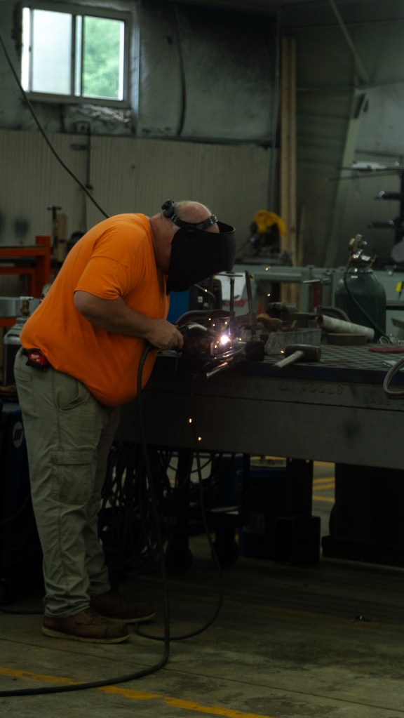 Close-up of a highly focused worker paying close attention to their job in a machine shop. The image showcases the worker’s intense concentration on ensuring top-quality results, highlighting attention to detail and precision. Emphasizes dedication and craftsmanship in a professional industrial setting.