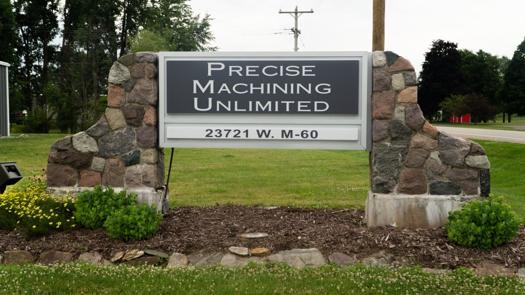 Shop sign for Precise Machining Unlimited featuring precision CNC machining, metal fabrication, and tooling services in an industrial setting.